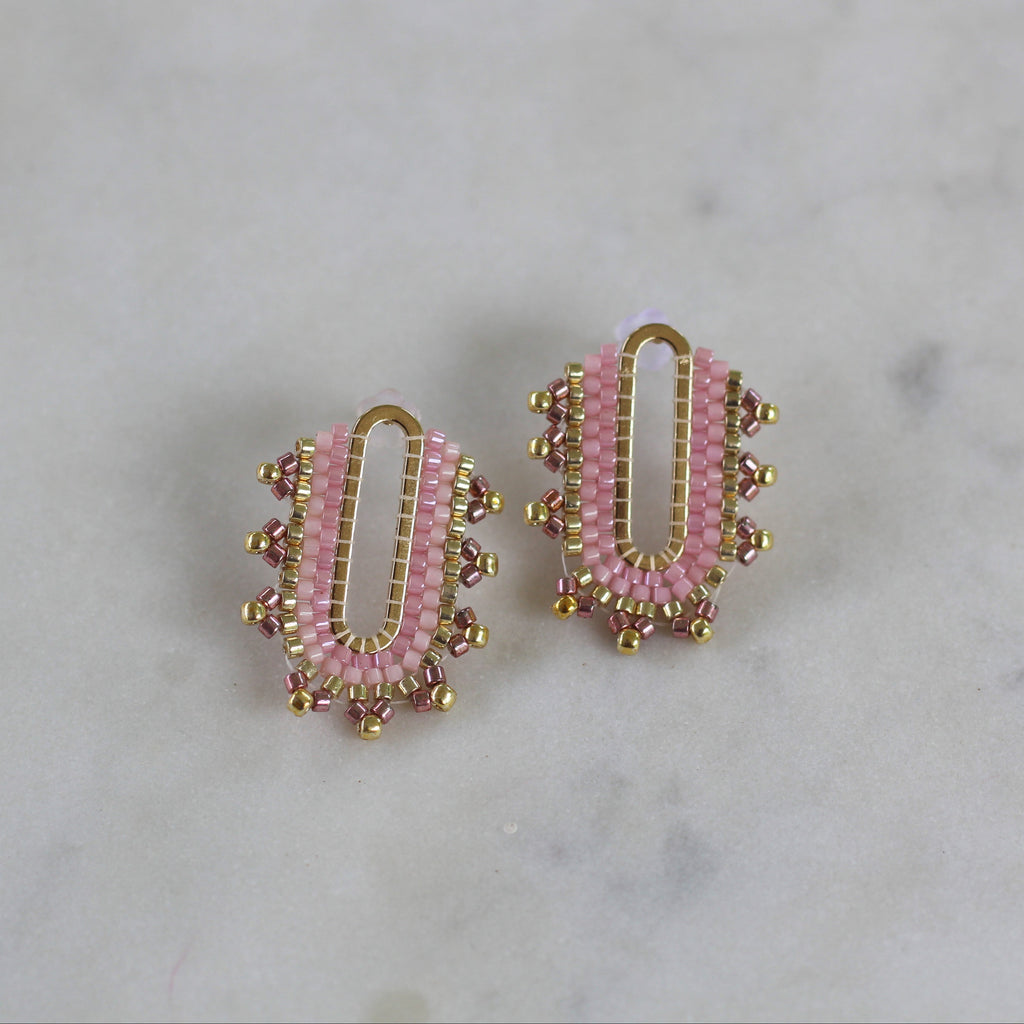 Pair of pink beaded earrings with gold accents on a marble background